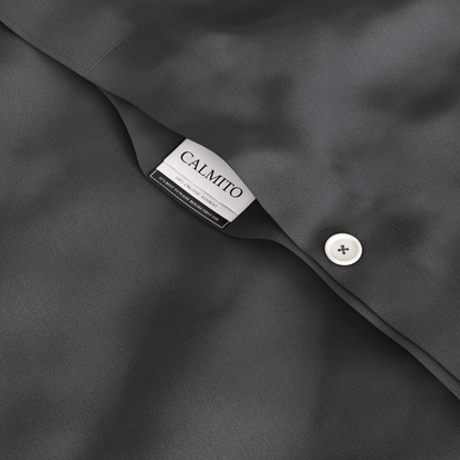 Close-up of a dark gray fabric with a Calmito label and button.
